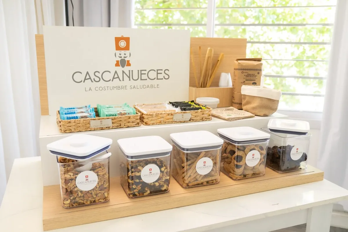 Healthy Station de Cascanueces: frascos herméticos con frutos secos, mixes y cookies, barritas y yerba en una oficina